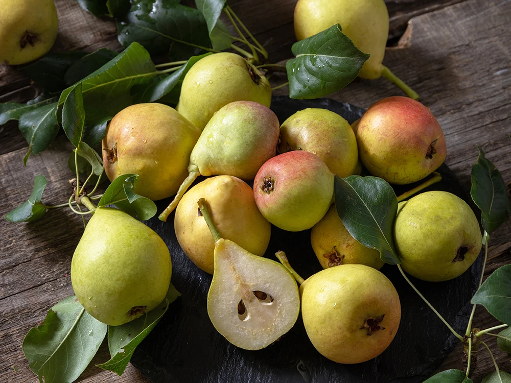 Frische Birnen mit Blättern auf rustikalem Holztisch, fotografiert für den Früchtehandel Dähler im Thurgau.